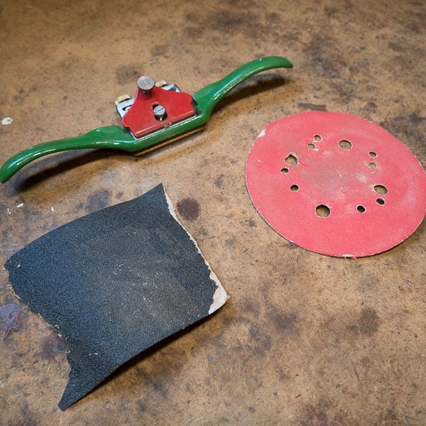 Spokeshave and sandpaper. Tools for smoothing wood handles.